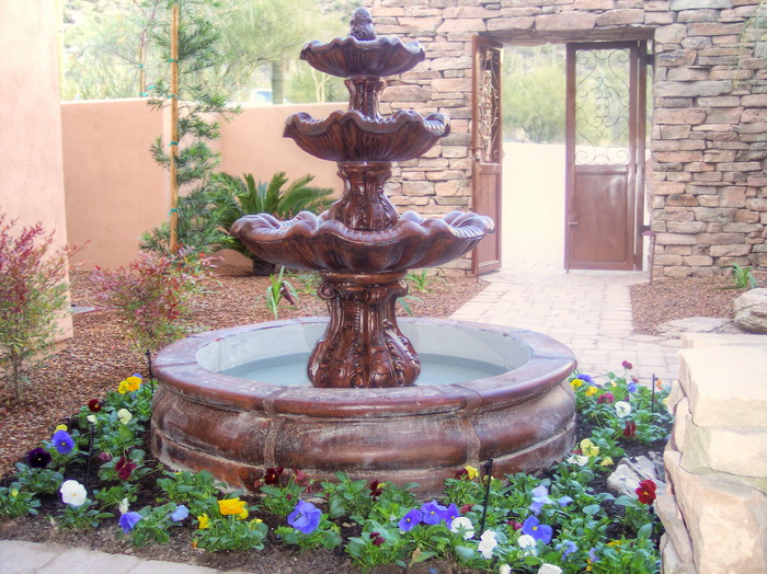 Formal courtyard entry with a tiered stone fountain and flower beds