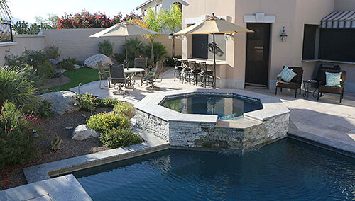 Pool and raised spa patio with stone accents and outdoor seating
